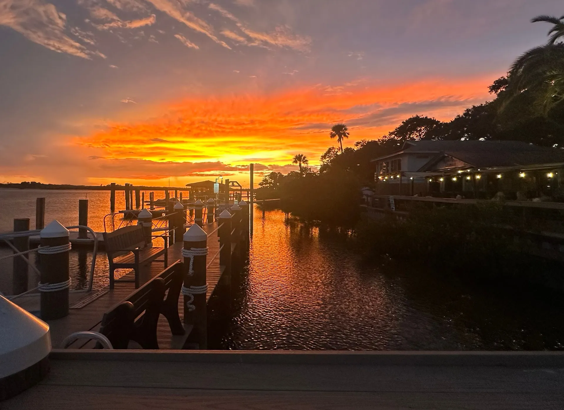 Orange sunset glowing across the water beside the Hidden Treasure waterfront dining deck