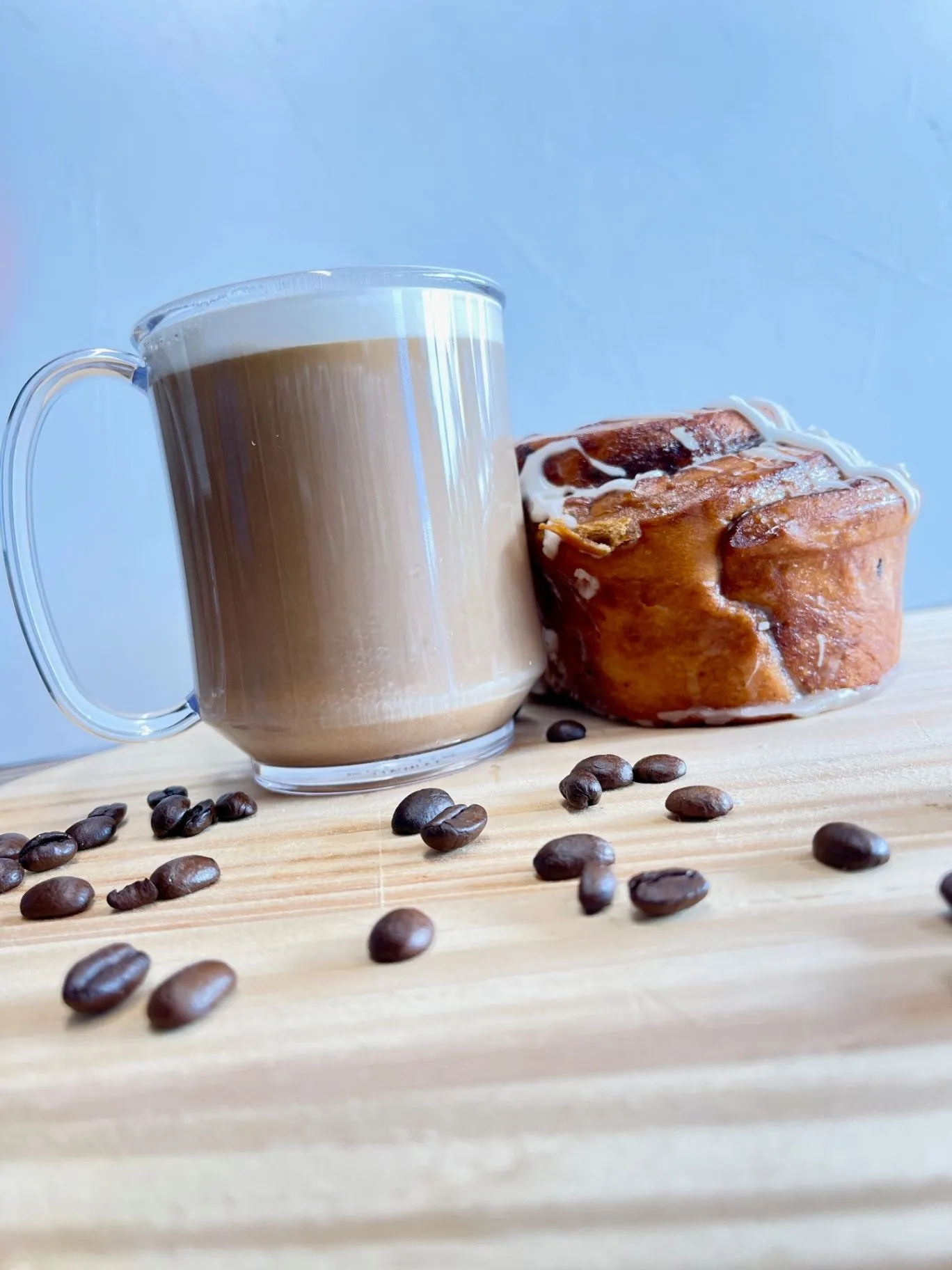 Latte and glazed pastry with coffee beans on a wooden table